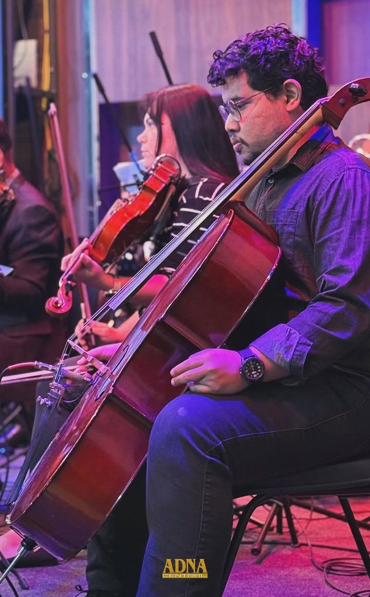 Roney Petherson tocando violoncelo em apresentação com a orquestra